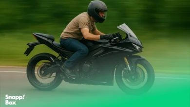 A man with a black helmet riding a black motorcycle fast