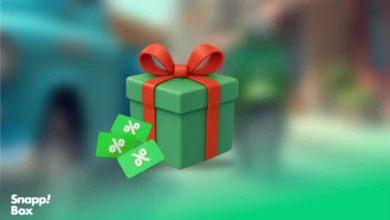 A green gift box with a red ribbon and 3 discount icons beside it