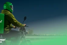 A Snapp! Box courier with a branded box on his motorcycle riding on a road