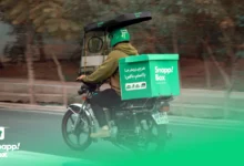 A Snapp! Box courier riding a motorcycle with a branded box