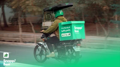 A Snapp! Box courier riding a motorcycle with a branded box