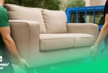 Two workers carrying a sofa to a blue pickup truck