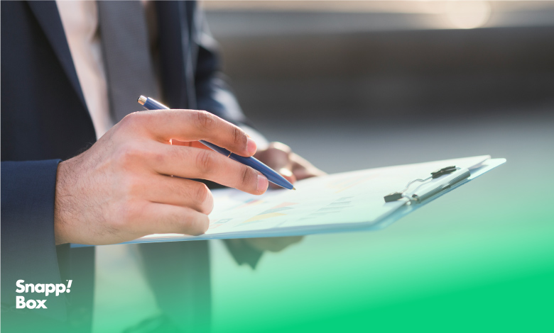 دستان یک مرد که یک چک‌لیست راه‌اندازی کسب‌وکار و یک خودکار را نگه داشته است