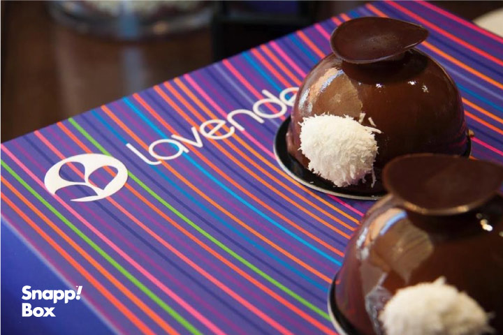 دو عدد کیک شکلاتی مینی روی یک زیربشقابی با آرم شیرینیفروشی لوندر