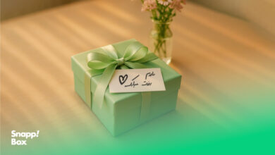 گل به همراه جعبه‌ی کادوی سبز با یادداشت «مادرم روزت مبارک»