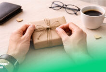 دستان پدری که در حال باز کردن یک کادو روی یک میز است