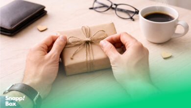 دستان پدری که در حال باز کردن یک کادو روی یک میز است